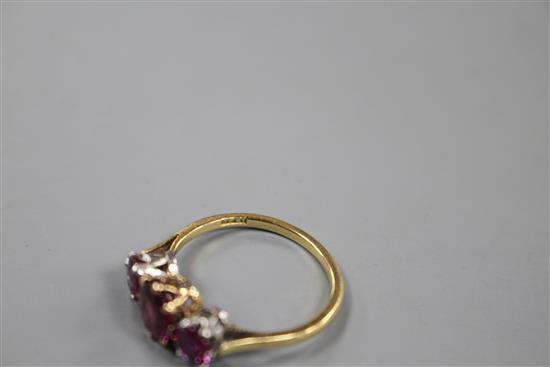 An 18ct and three stone ruby and garnet?? set dress ring, size M, gross 2.7 grams.